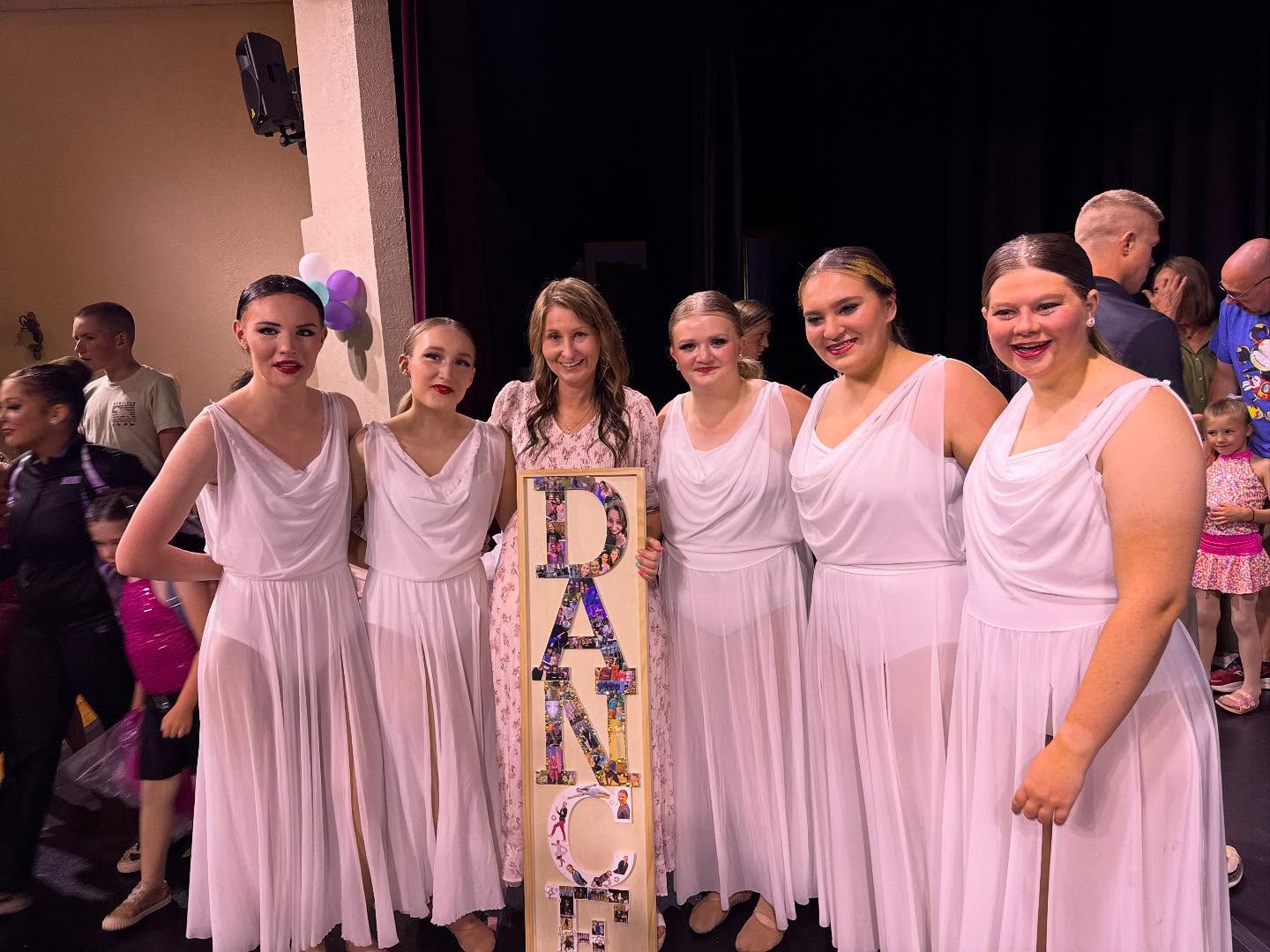 Dancers in white recital dresses with their teacher